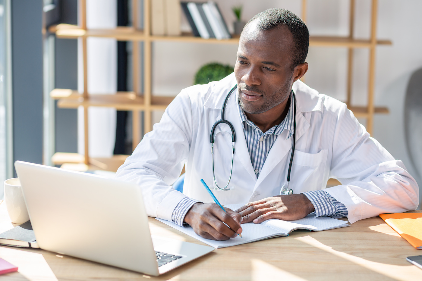 doctor working on laptop taking notes